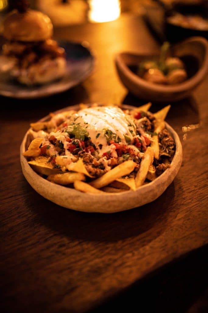a wooden table topped with a bowl of fries